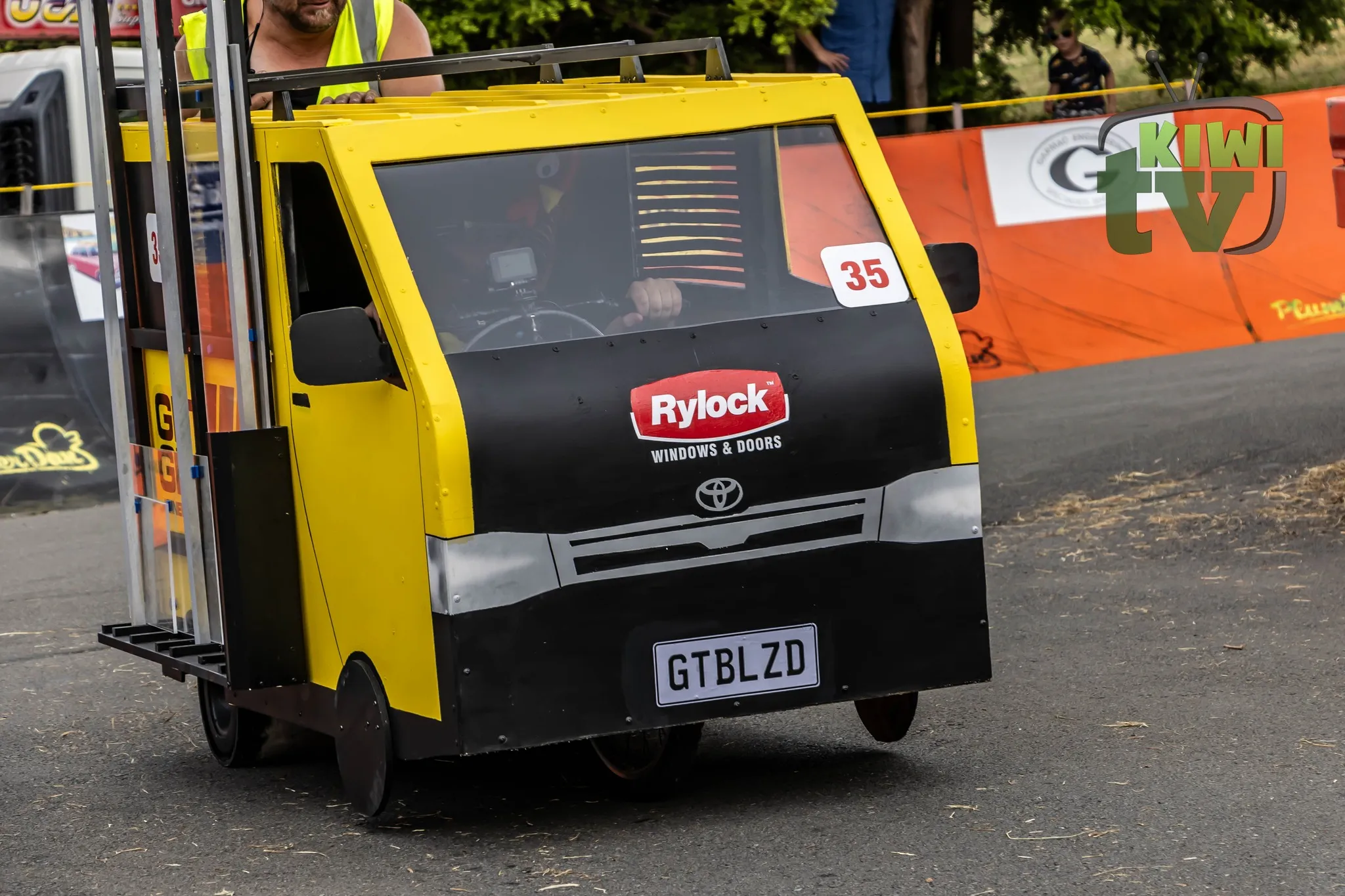 Crowds cheering as a soap box kart leans into the curve