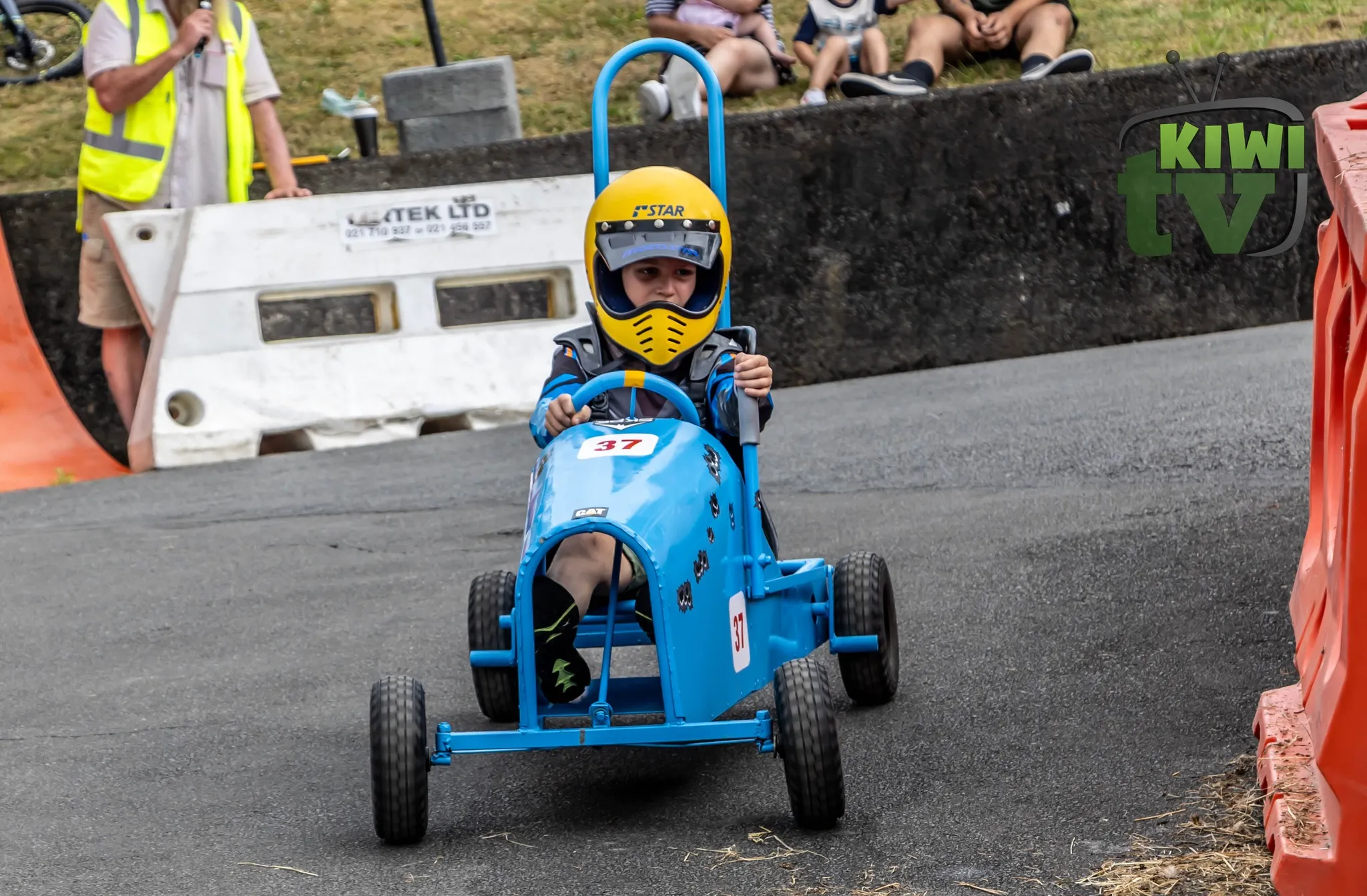 Soap box kart lined up under start arch with rainbows overhead